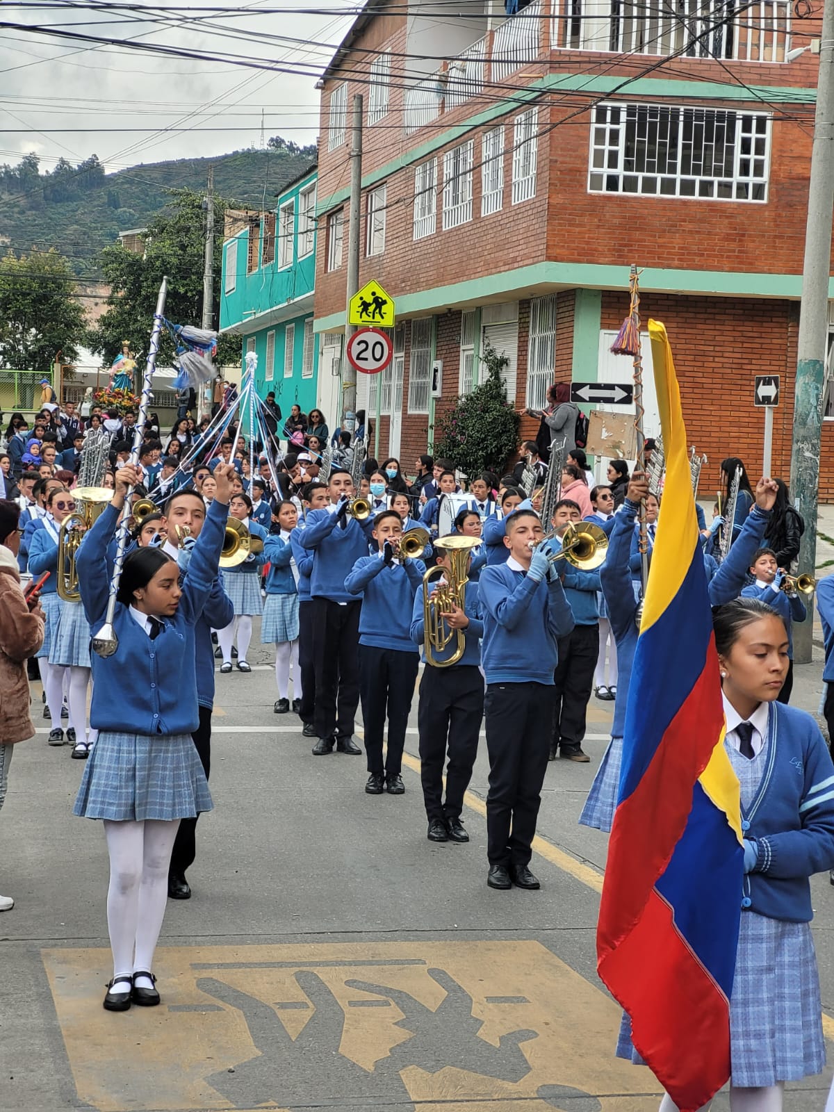 Estudiantes de la banda marcial escolar desfilan en una calle.